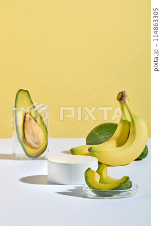 Unique design for advertise product manufactured from banana and avocado on yellow background with a blank platform displayed in the middle of white table for showing product, copy space for text 114863305