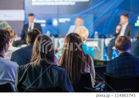 Audience listening to panel discussion at business conference 114863743