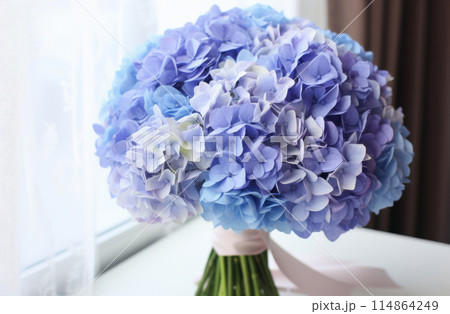 A bouquet of blue hydrangea on a table. 114864249
