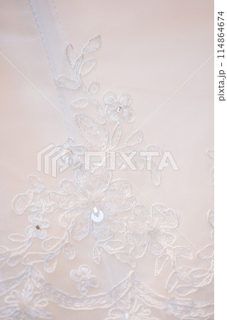 Bridal gown has white lace with intricate patterns, showcasing sophistication and beauty 114864674