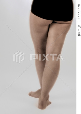 A womans legs clad in black underwear in a minimalist studio setting, exuding elegance and grace 114864776