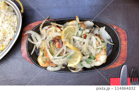 Savor the taste of Grilled Chicken and Rice served on a wooden plate with a zesty lemon garnish Savor the taste of Grilled Chicken and Rice served on a wooden plate with a zesty lemon garnish 114864832