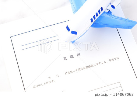 オフィスのデスクの上に置かれた退職届と飛行機で、これから会社を辞めて、自由に羽ばたくイメージ オフィスのデスクの上に置かれた退職届と飛行機で、これから会社を辞めて、自由に羽ばたくイメージ 114867068