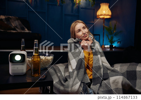 Cute smiling woman watching romantic movie on projector 114867133