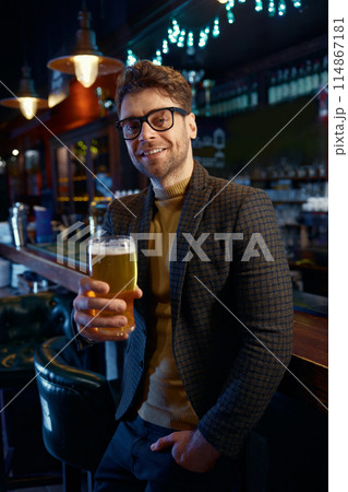 Portrait of relaxed businessman with glass of foamy beer in bar Portrait of relaxed businessman with glass of foamy beer in bar 114867181
