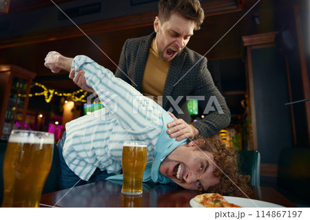 Drunk friends football fans fighting at sports bar due to quarrel 114867197