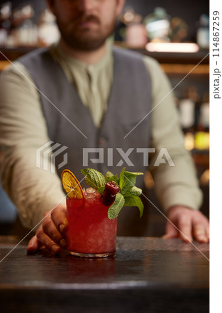 Portrait of bartender giving cocktail to client of nightclub or hotel bar Portrait of bartender giving cocktail to client of nightclub or hotel bar 114867259