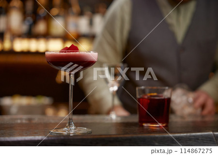Pink cocktail decorated with rose floral petal on wooden bar counter desk 114867275