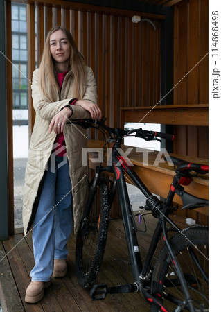 Woman Standing Next to Bike on Wooden Platform 114868498