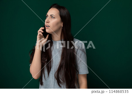 Woman Talking on Cell Phone in Front of Green Wall Woman Talking on Cell Phone in Front of Green Wall 114868535