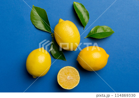 Many fresh ripe lemons with green leaves on colored background, top view, space for text 114869330