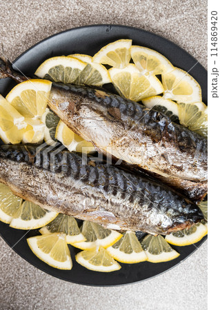 Oven-baked mackerel sea fish dish served with fresh lemon slices Oven-baked mackerel sea fish dish served with fresh lemon slices 114869420