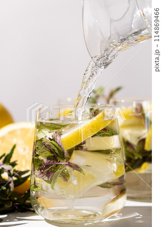 Lemon water with mint pouring into glass. Lemon water with mint pouring into glass. 114869466