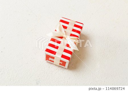 Wrapped christmas or other holiday handmade present in paper with colored ribbon. Present box, decoration of gift on table, top view with copy space 114869724
