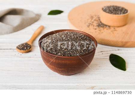 Chia seeds in bowl and spoon on colored background. Healthy Salvia hispanica in small bowl. Healthy superfood Chia seeds in bowl and spoon on colored background. Healthy Salvia hispanica in small bowl. Healthy superfood 114869730