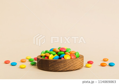 Multicolored candies in a bowl on a colored background. birthday and holiday concept. Top view with copy space 114869863