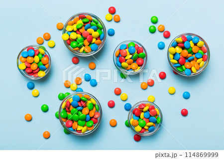 different colored round candy in bowl and jars. Top view of large variety sweets and candies with copy space different colored round candy in bowl and jars. Top view of large variety sweets and candies with copy space 114869999