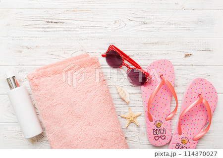 Summer holiday concept. Top view of beach towel, flip flop and sunscreen cream on table Top view with copy space for text Summer holiday concept. Top view of beach towel, flip flop and sunscreen cream on table Top view with copy space for text 114870027