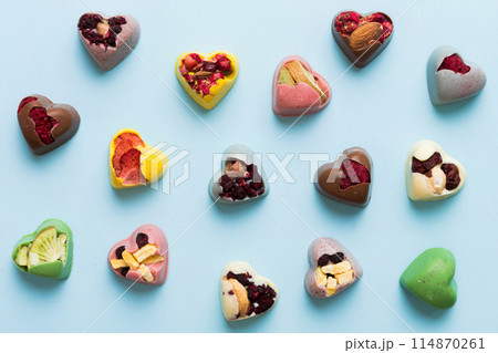 chocolate sweets in the form of a heart with fruits and nuts on a colored background. top view with space for text, holiday concept 114870261