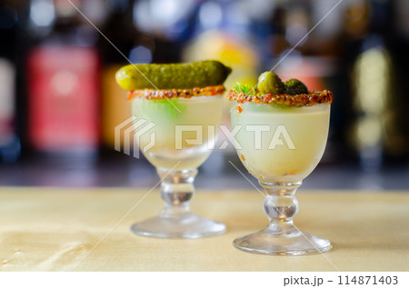 Shaken vodka and pickle juice with ice in a shot glass and garnished with small pickled cucumber and dill Shaken vodka and pickle juice with ice in a shot glass and garnished with small pickled cucumber and dill 114871403
