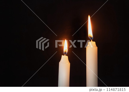 Two lit candles on a dark background 114871815