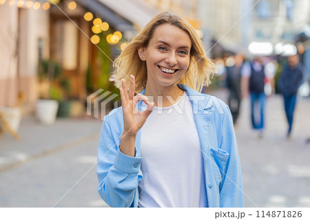 Young woman looking approvingly at camera showing OK gesture positive like sign Okay celebrate win 114871826