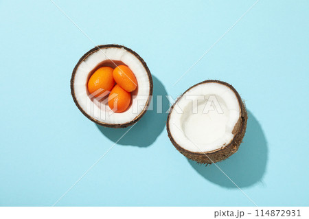 Two half of coconut and whole kumquat on blue background, top view 114872931