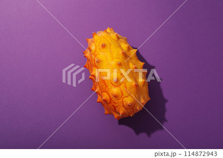 One whole kiwano fruit on purple background, top view One whole kiwano fruit on purple background, top view 114872943