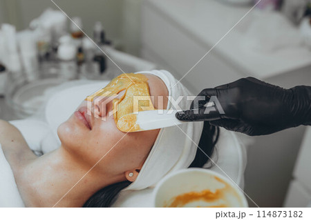 A girl at a cosmetologist does cosmetic procedures. Alginate mask 114873182