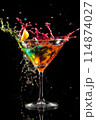 A martini glass containing a splash of liquid, set against a black background 114874027