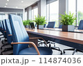 Conference room has tables, chairs, and plants, creating welcoming ambiance 114874036