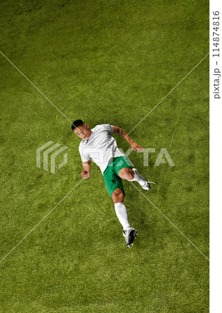 Dynamic photo of young sporty man, soccer player in mid-action, demonstrating hisskills on lush green sports field. Dynamic photo of young sporty man, soccer player in mid-action, demonstrating hisskills on lush green sports field. 114874816