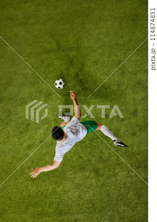 Top-down perspective of footballer executing powerful kick, showcasing their athletic prowess on pitch. 114874851