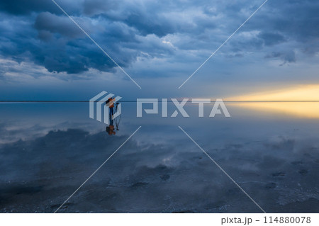 Photographer capturing dramatic skies over calm waters 114880078
