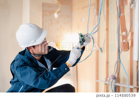 建築現場で配線工事をする電気工事士 114880539