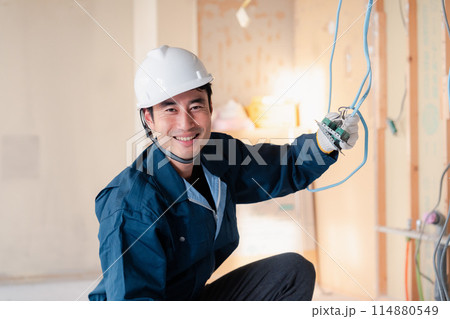 建築現場で配線工事をする電気工事士 114880549