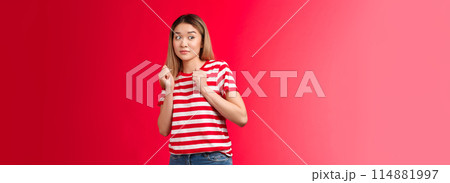 Alarmed silly blond asian girl wear striped t-shirt stay away suspicious person, press hands chest reluctant aversion, tilt back displeased hesitant express dislike shock, stand red background 114881997