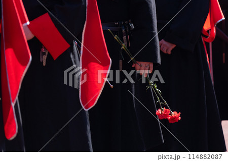 Cossacks in uniform lay flowers. Carnation flower in hand. Cossacks in uniform lay flowers. Carnation flower in hand. 114882087
