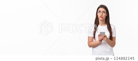 Communication, technology and lifestyle concept. Portrait of troubled and concerned young woman worried for friend, sending text message if shes okay and thinking, look up nervous, hold mobile phone 114882145