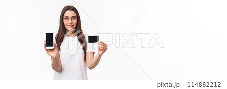 Portrait of excited and tempting young woman likes shopping, cant wait to use her new credit card in online store, showing mobile phone screen, brag with her bank account, bite lip thrilled 114882212