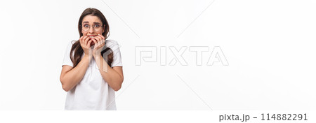 Waist-up portrait of scared young brunette girl in panic, exams are near feel frightened, biting fingers and staring terrified, trembling fear, standing white background afraid 114882291