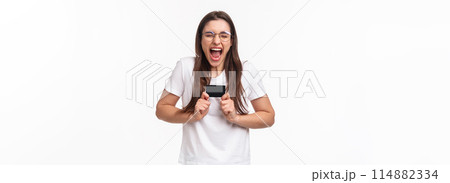 Portrait of excited female shopaholic cant wait to waste all money on her bank account, got new credit card, screaming from excitement and thrill, happy to shopping her favorite online store Portrait of excited female shopaholic cant wait to waste all money on her bank account, got new credit card, screaming from excitement and thrill, happy to shopping her favorite online store 114882334