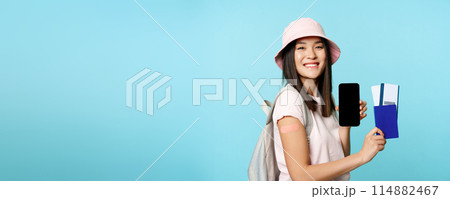 Happy smiling tourist got vaccine from covid-19, showing mobile phone screen and passport with tickets to travel abroad, vaccination certificate on smartphone app 114882467