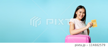 Happy smiling asian woman, tourist with suitcase showing international vaccination certificate from covid-19, getting vaccine from coronavirus for travelling abroad 114882579