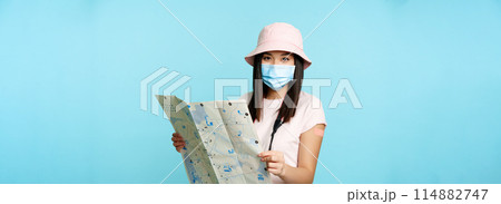 Vaccinated korean woman in medical face mask, holding tourist map, visiting sightseeing on journey 114882747