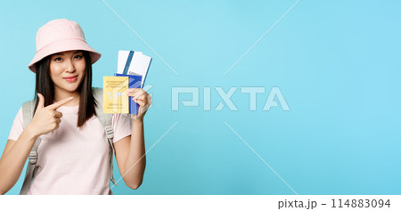 Smiling korean tourist shows her passport, vaccination certificate from coronavirus disease, getting vaccine shot to travel, standing over blue background Smiling korean tourist shows her passport, vaccination certificate from coronavirus disease, getting vaccine shot to travel, standing over blue background 114883094
