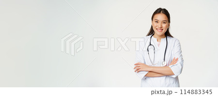 Healthcare and medical concept. Smiling female asian doctor in uniform, looking confident at camera, treating patients, standing over white background Healthcare and medical concept. Smiling female asian doctor in uniform, looking confident at camera, treating patients, standing over white background 114883345