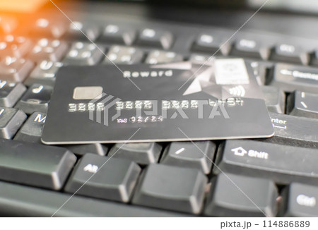 A black credit card with the word "Reward" on it is sitting on a keyboard A black credit card with the word "Reward" on it is sitting on a keyboard 114886889
