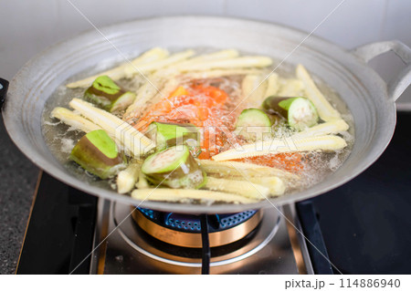 A pan of vegetables is being cooked on a stove A pan of vegetables is being cooked on a stove 114886940