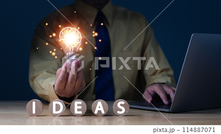 A man is holding a light bulb and the words "ideas" are written in front of him 114887071